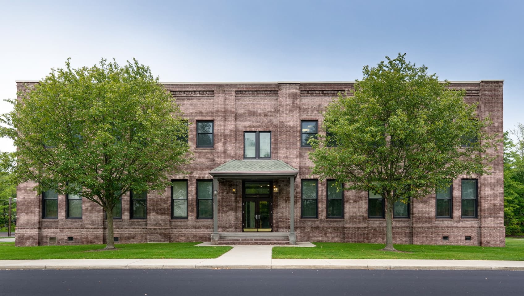 Traditional brick professional office building in northern New Jersey framed by mature oak trees under overcast daylight