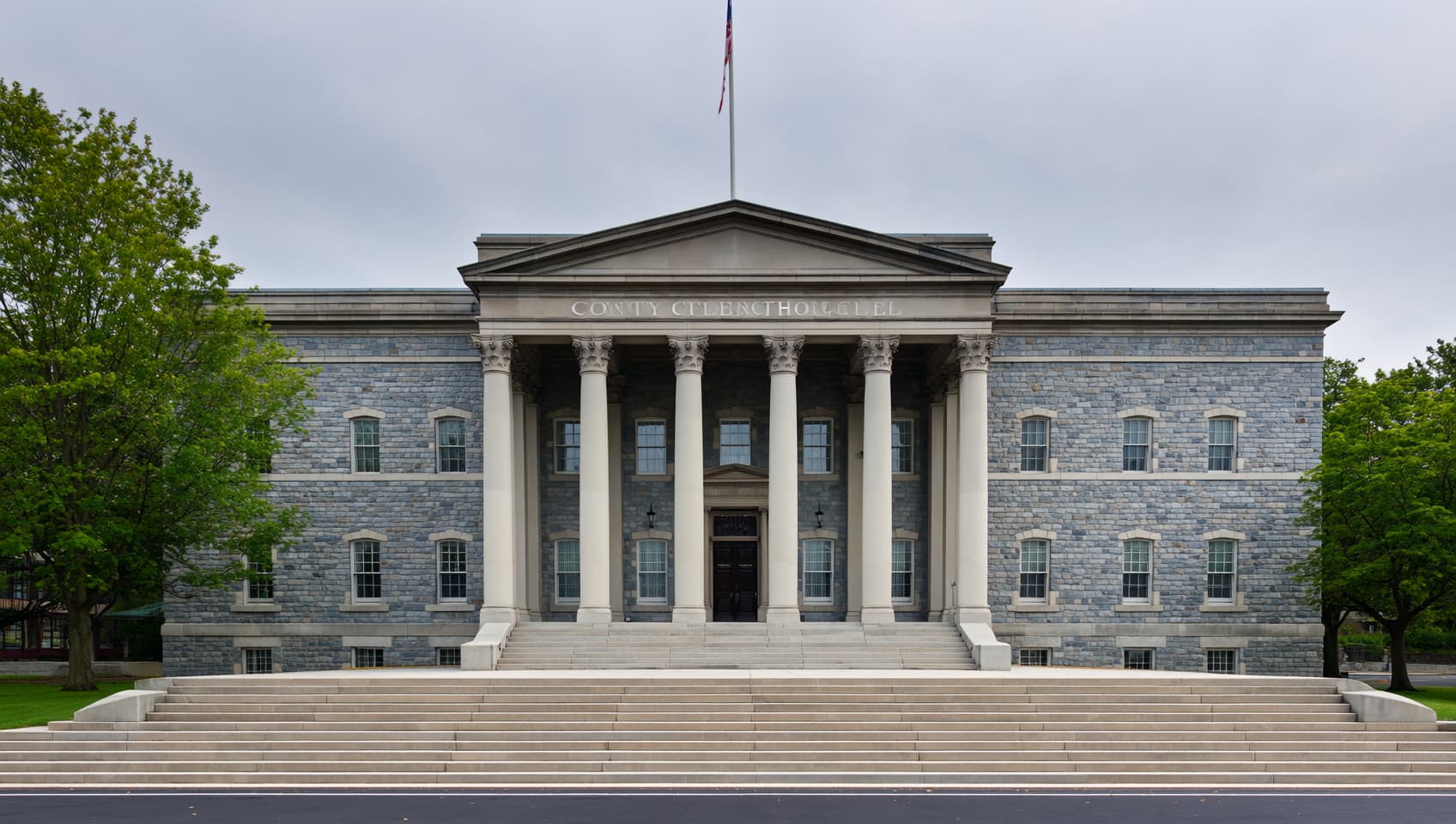 Stone steps and columned entry of a traditional New Jersey county courthouse under flat overcast light
